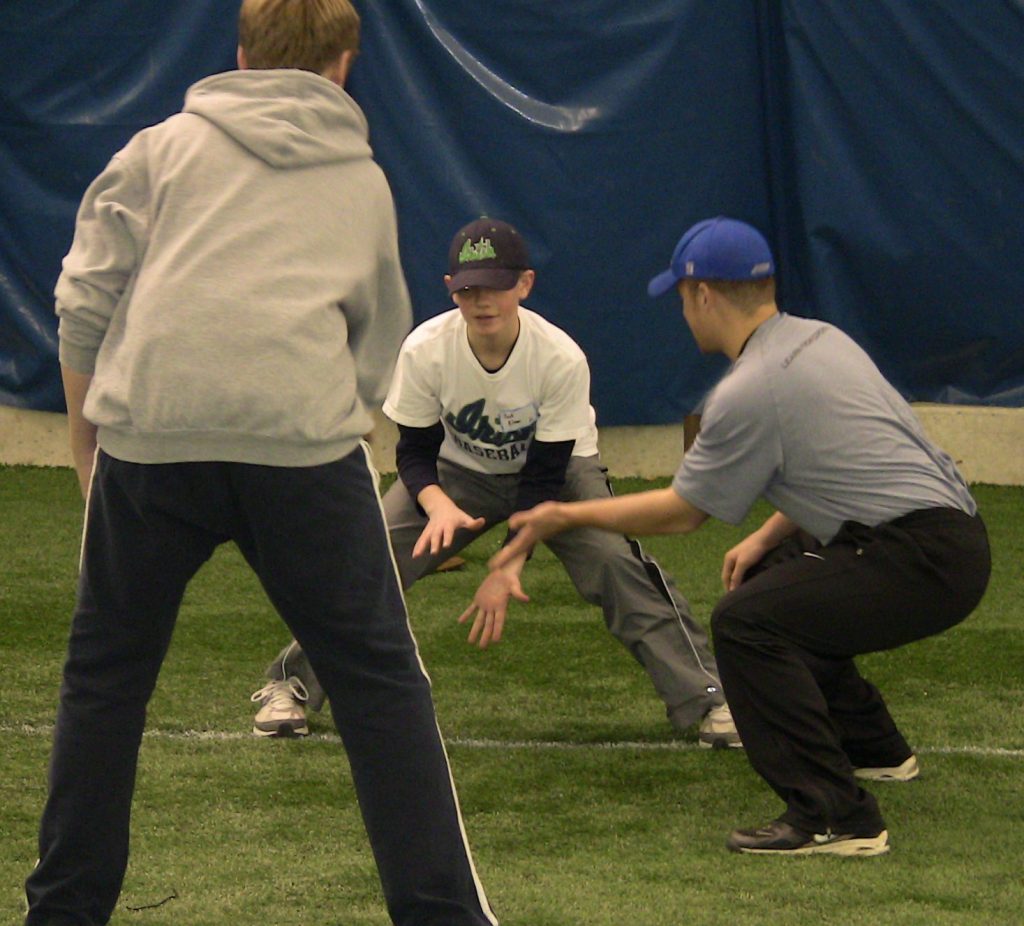 Baseball lessons in a small group teaching fielding to a youth player and focusing on fundamentals.